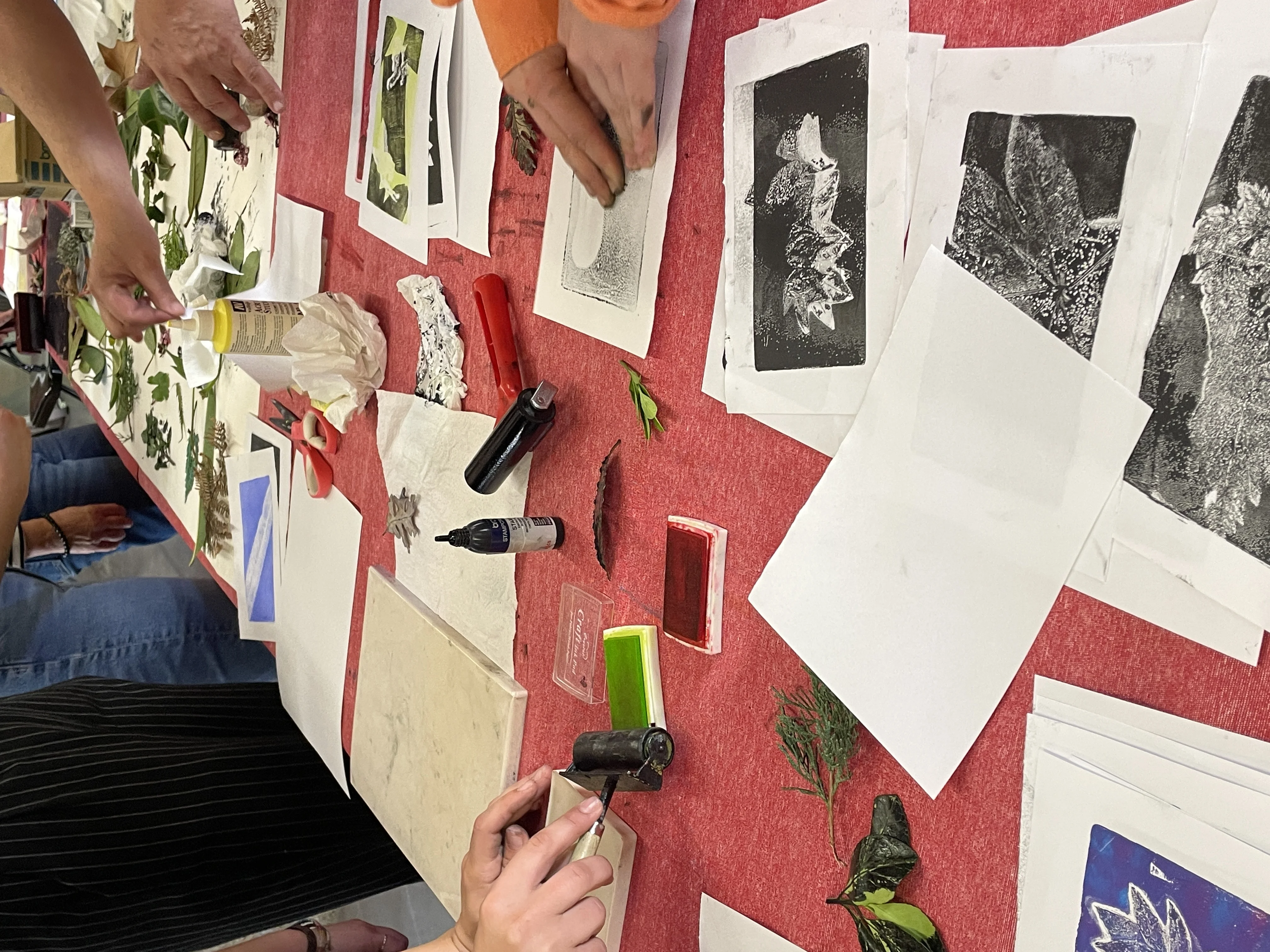 Participantes trabajando con planchas de gel y plantas en el taller de estampación